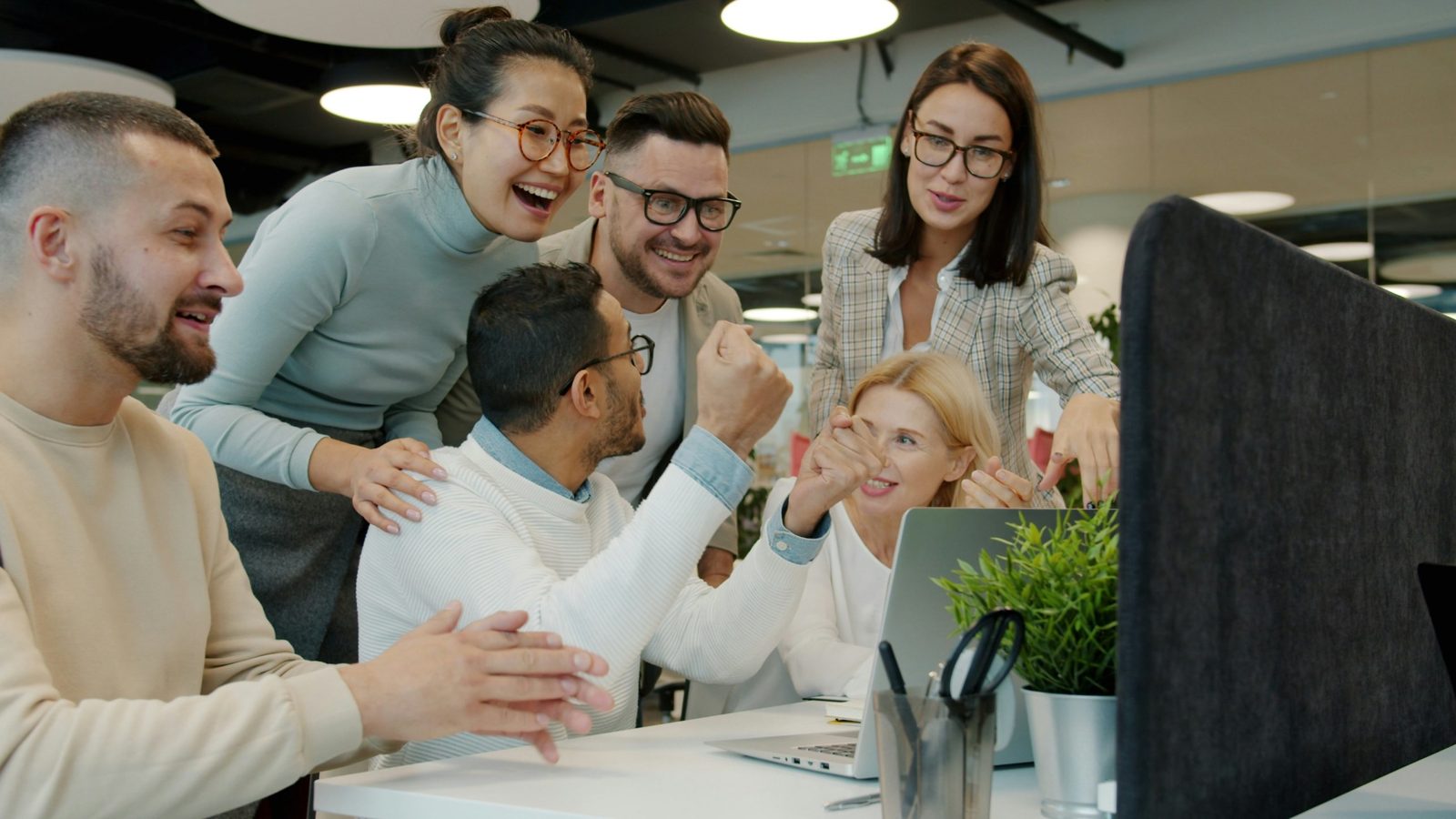 Team freut sich gemeinsam vor einem Laptop