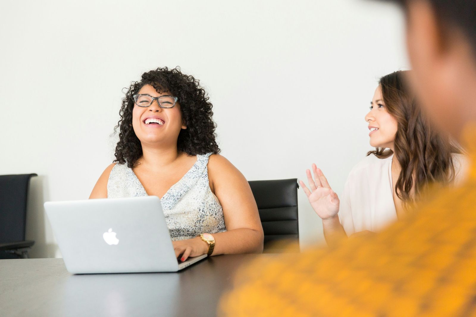 Zwei Frauen im Gespräch an einem Tisch mit Laptop