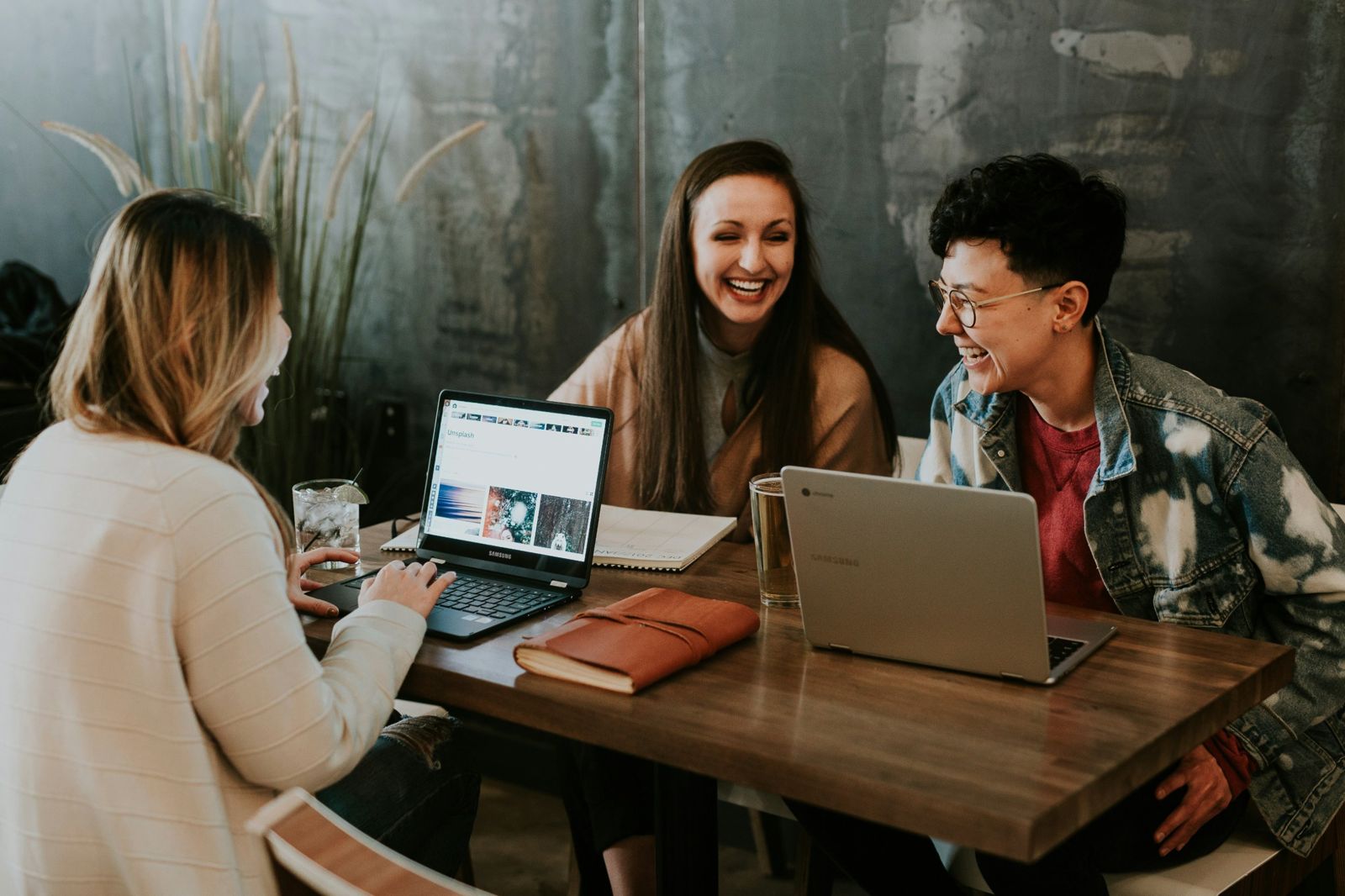 Drei Personen im Gespräch an einem Tisch mit Laptops